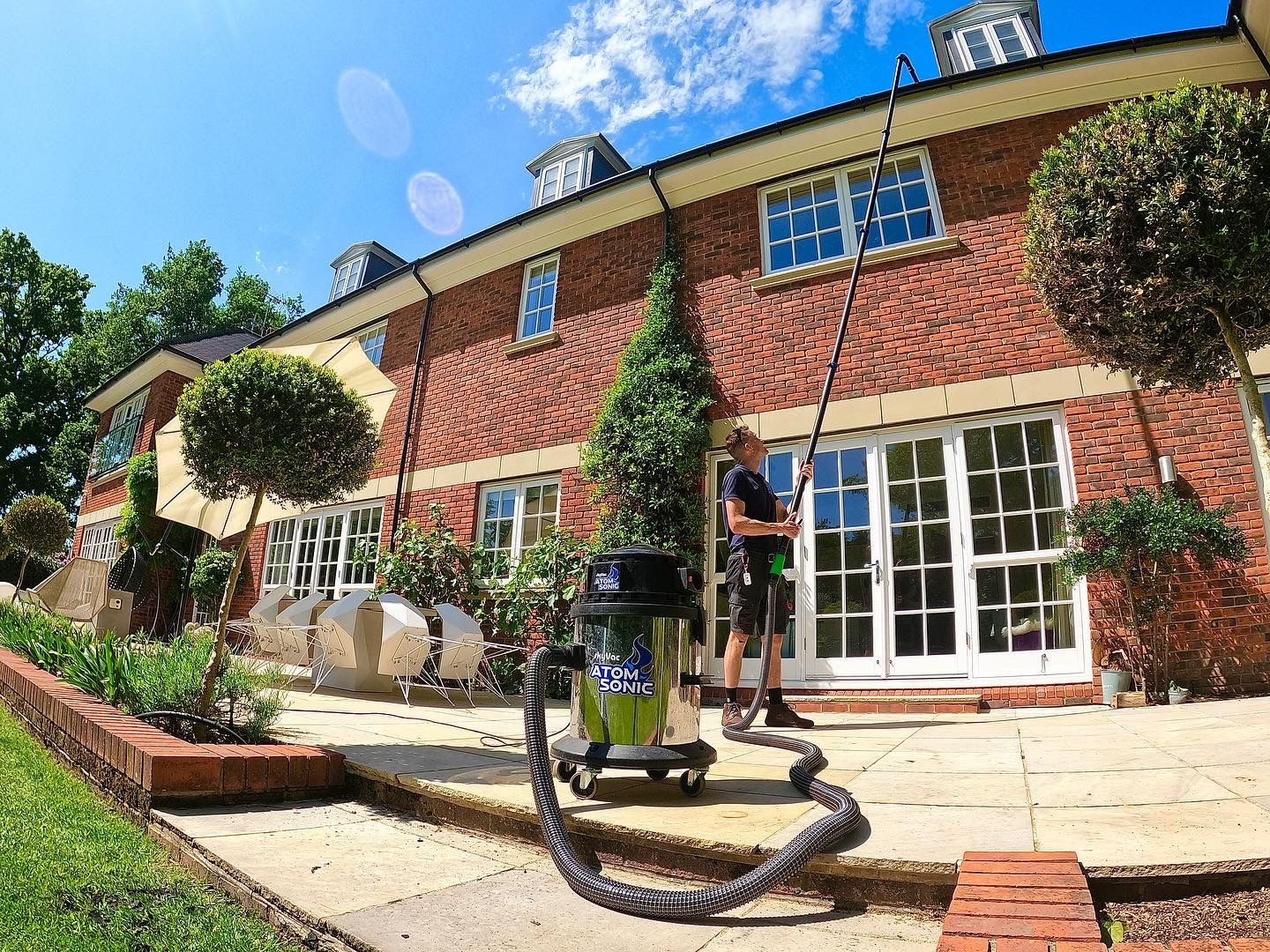Gutter cleaning in Ascot using a high-reach vacuum on a tall Victorian house surrounded by pine trees